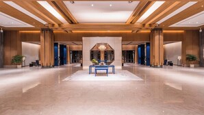 A spacious lobby with a central seating area, wooden ceiling beams, and a large chandelier. - Pujin Hotel (Jiaxing)