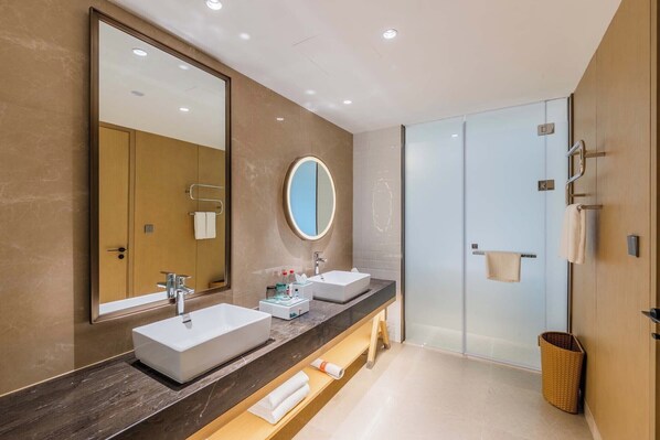 A modern bathroom with two sinks, a large mirror, and a glass shower enclosure.