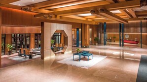 A spacious lobby with a polished floor, seating areas, and a reception desk. - Pujin Hotel (Jiaxing)