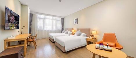 A hotel room with two beds, a desk, a chair, a small table, and a TV on the wall.