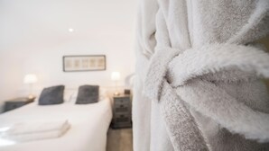 Ein Hotelzimmer mit einem Bett, zwei Nachttischen und einem über einem Stuhl drapierten Bademantel.