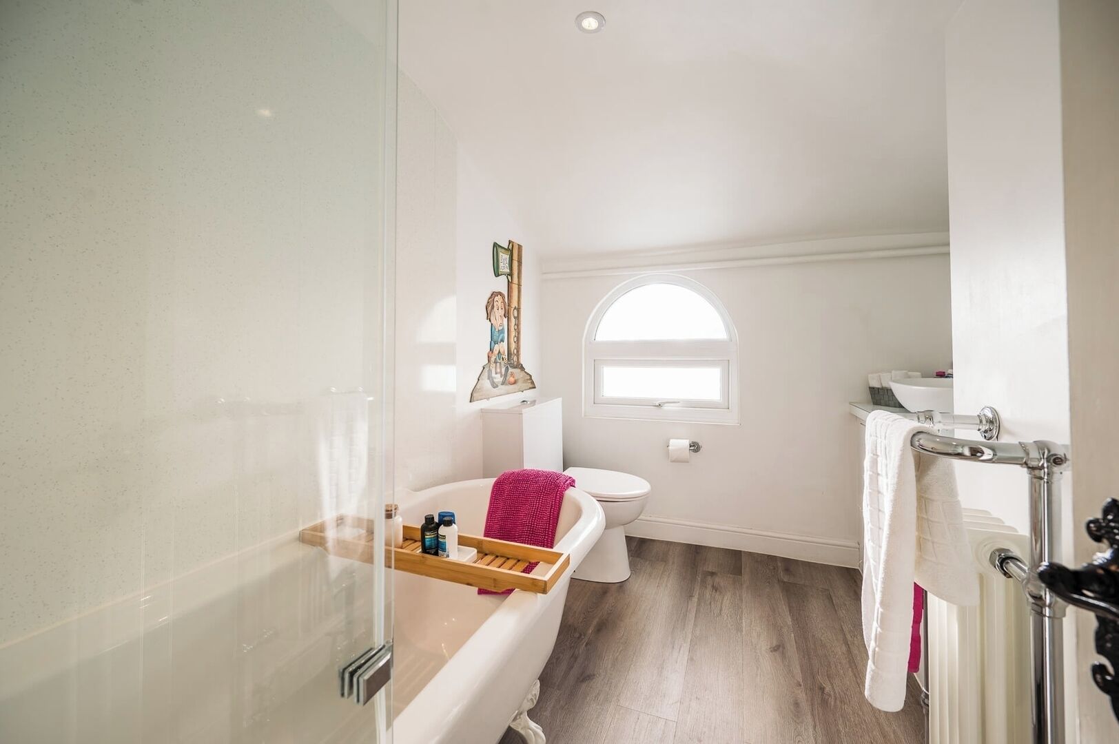 A bathroom with a bathtub, toilet, and a window.