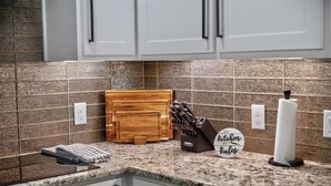 A kitchen with a granite countertop, wooden cutting board, knife block, and a sign that says "My Kitchen My Rules." - Luxury Frisco Home w/Private Pool, Game Room, 85" TV, Cozy Patio & Huge Backyard (Frisco)