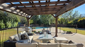 An outdoor patio with a pergola, seating area, and a pool. - Luxury Frisco Home w/Private Pool, Game Room, 85" TV, Cozy Patio & Huge Backyard (Frisco)