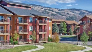 A multi-story residential building with balconies, a parking lot, and a mountainous backdrop. - 3BR, sleep 8, Club Wyndham, ski shuttle, pool, spa in Steamboat Springs (Steamboat Springs)
