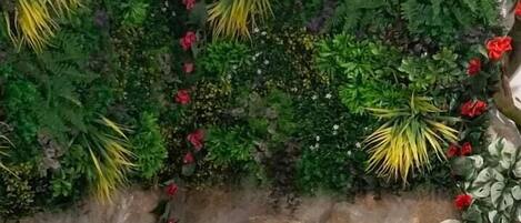 Une salle de bain avec un mur en pierre, une baignoire blanche et des éléments de décoration à base de feuillage vert.