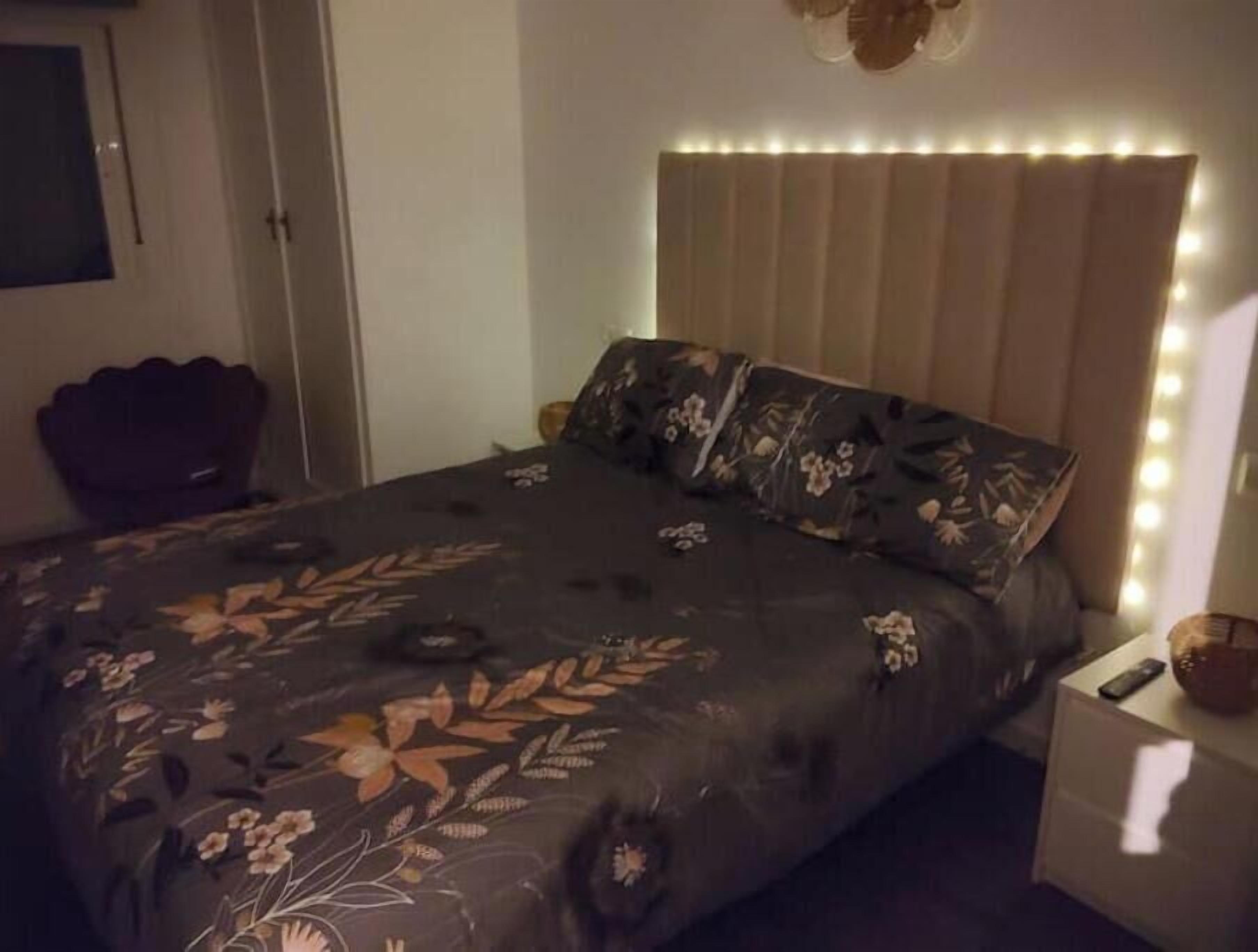 Una camera da letto con un letto, un comodino, una lampada a parete e una porta.
