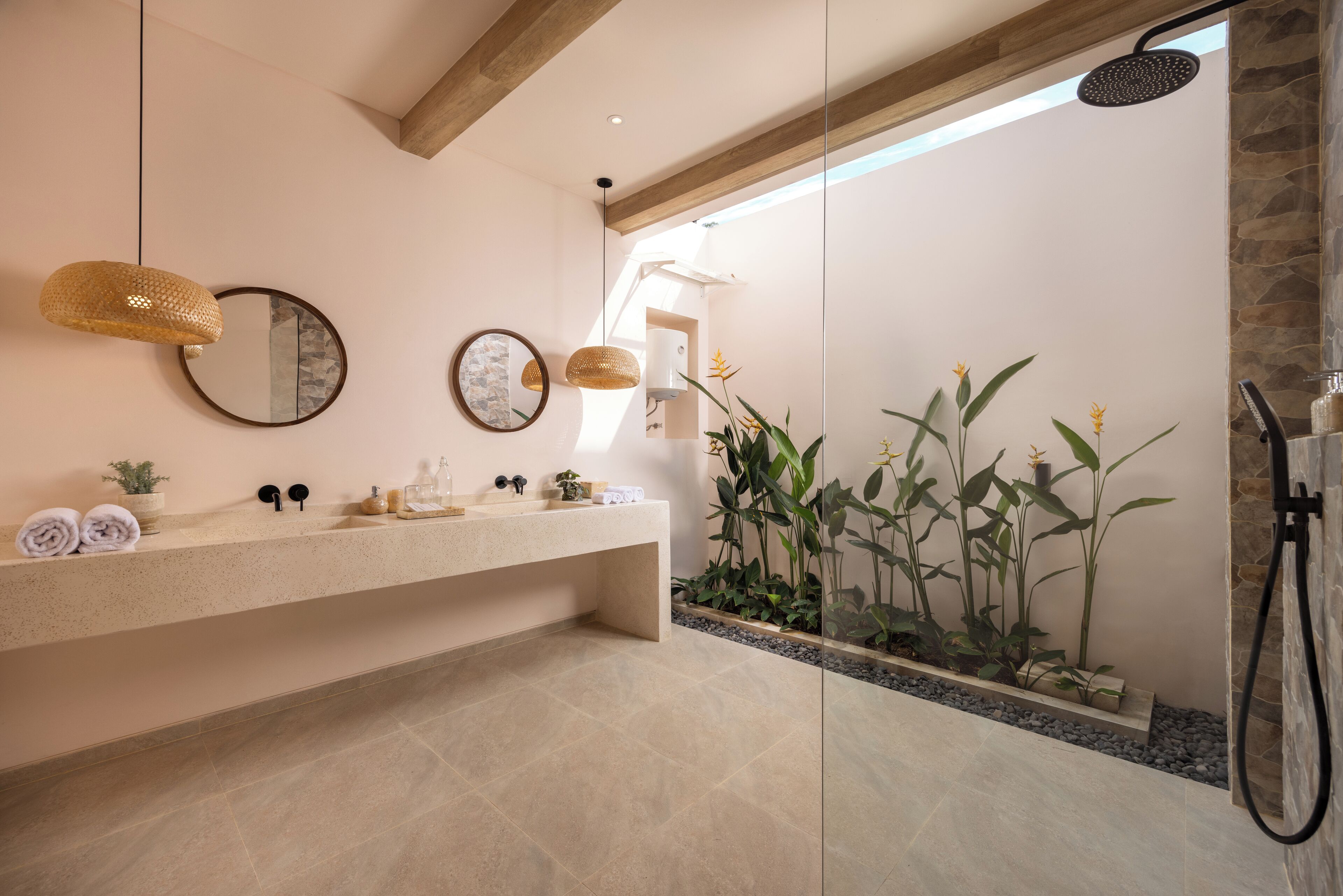 A modern bathroom with a large mirror, a sink with toiletries, a shower, and a plant area.