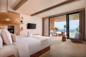 Habitación de hotel moderna con una cama grande, un televisor de pantalla plana, un balcón con asientos y vista al océano.