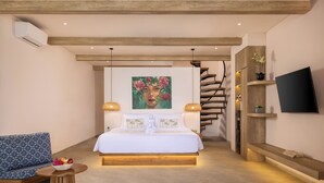 Un dormitorio moderno con una cama grande, una escalera, un televisor y una pequeña mesa con fruta.