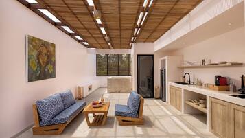 A modern kitchen with wooden cabinets, a built-in oven, and a sink. There is a dining area with a sofa and a coffee table.