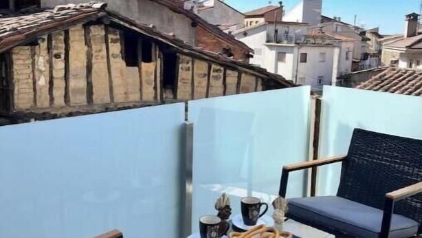 A balcony with two chairs, a small table with a plate of pretzels and a mug, and a clear view of the surrounding buildings. - Mabel House Suites - Intimate and sensory experience in Sierra de Gredos (Mijares)