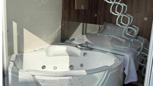 A modern bathroom with a glass-enclosed jacuzzi, a wooden vanity, and a mounted TV. - Mabel House Suites - Intimate and sensory experience in Sierra de Gredos (Mijares)