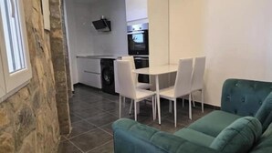 A compact living space with a dining area, kitchenette, and a green sofa. - Mabel House Suites - Intimate and sensory experience in Sierra de Gredos (Mijares)