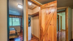 A room with a bed, a washing machine, and a wooden door. - Outlaw Cabin - Newly Renovated, Covered Deck, Tons of Wildlife (Ruidoso)