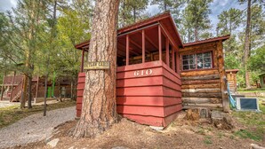A rustic cabin with a number 610 sign, surrounded by trees and a gravel path. - Outlaw Cabin - Newly Renovated, Covered Deck, Tons of Wildlife (Ruidoso)