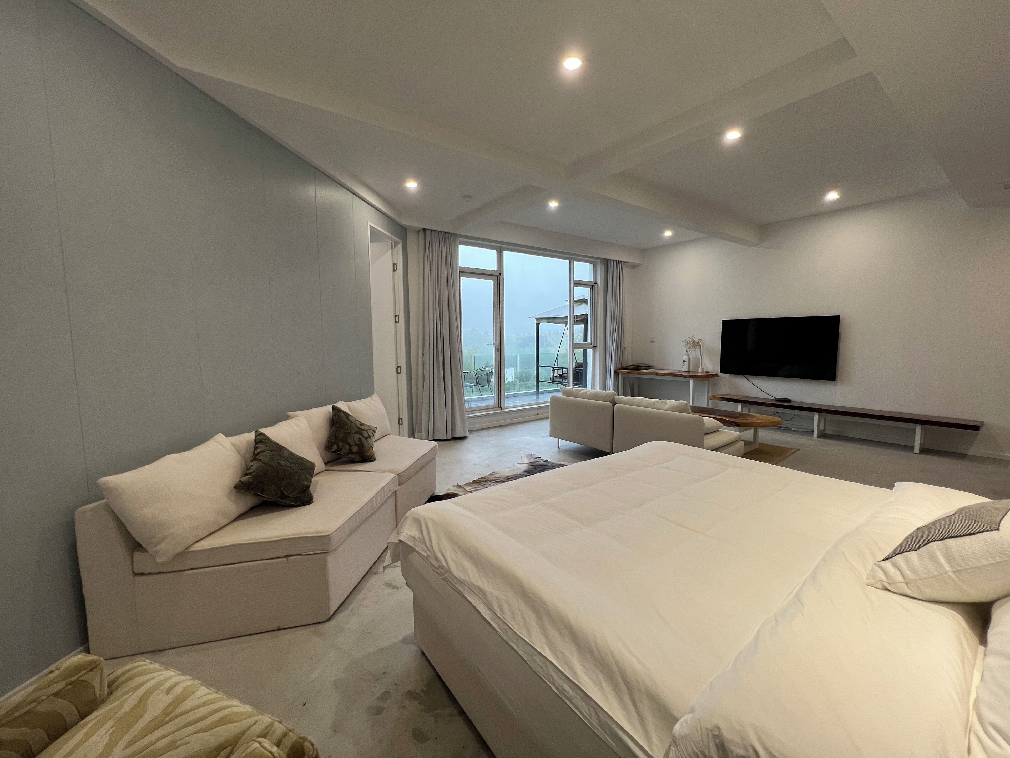 Una habitación de hotel moderna con una cama grande, un sofá, un escritorio y un televisor.