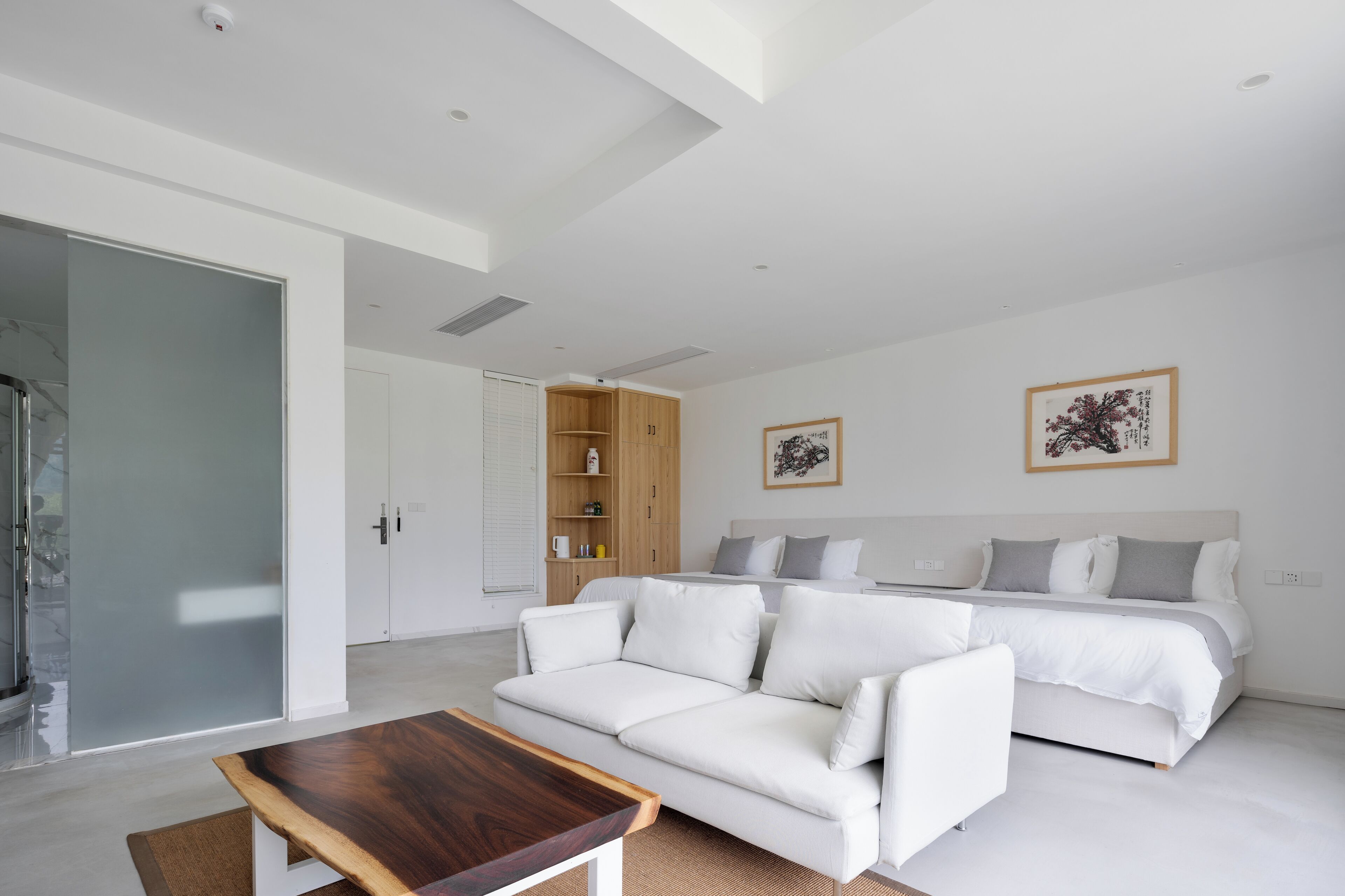 A modern bedroom with a large bed, a white sofa, and a wooden coffee table.