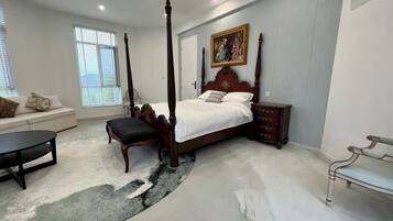 Un dormitorio con cama con dosel, una mesita de noche, un banco y un sofá.