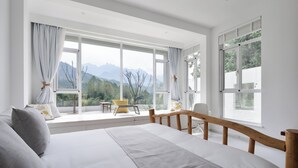 A bedroom with a large window, a bed, a wooden bench, and a small table with chairs. - daiyungui (Huangshan)