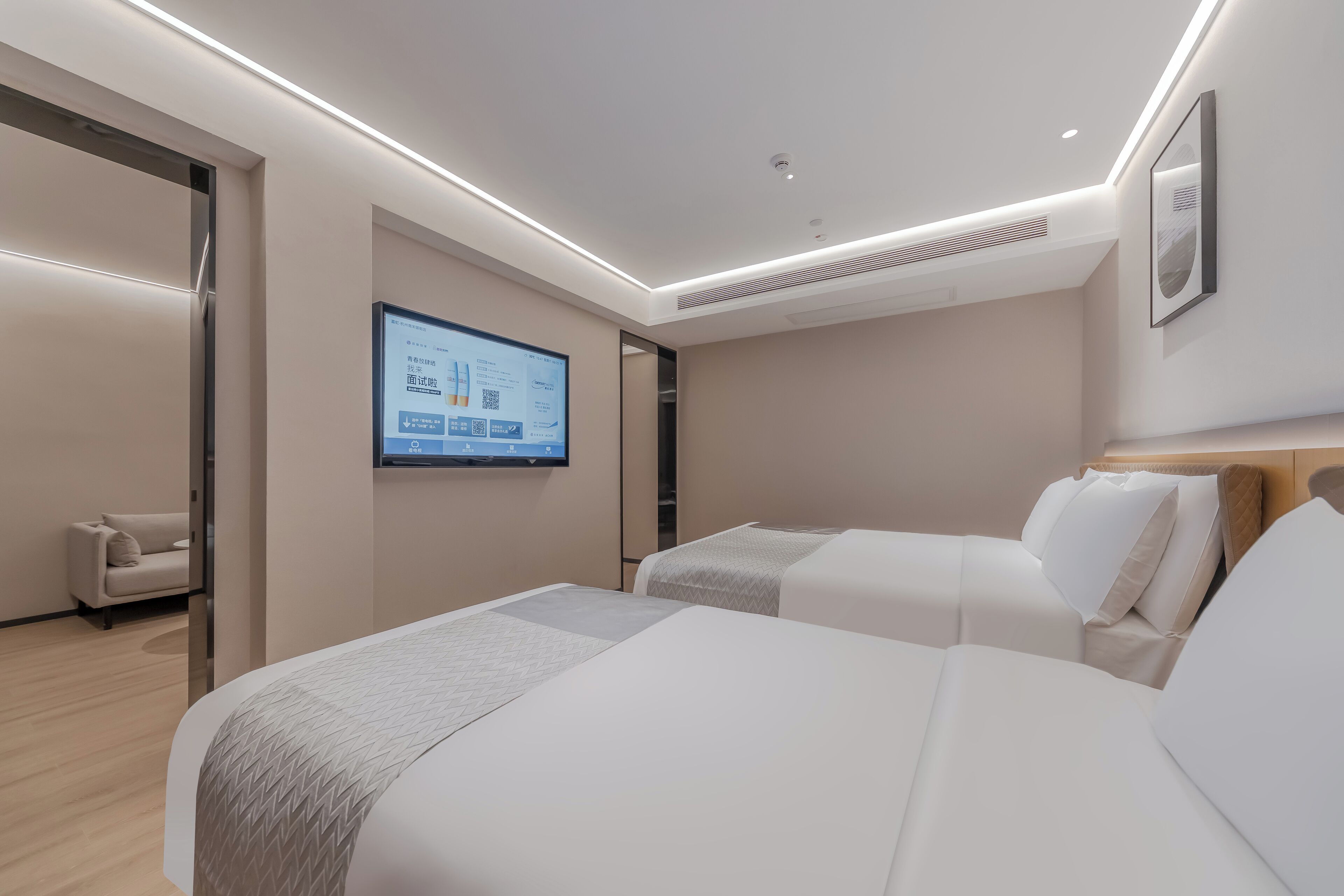 A modern hotel room with two beds, a flat-screen TV mounted on the wall, and a minimalist design.