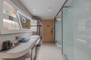 Un baño moderno con un espejo grande, dos lavamanos y una zona de ducha.