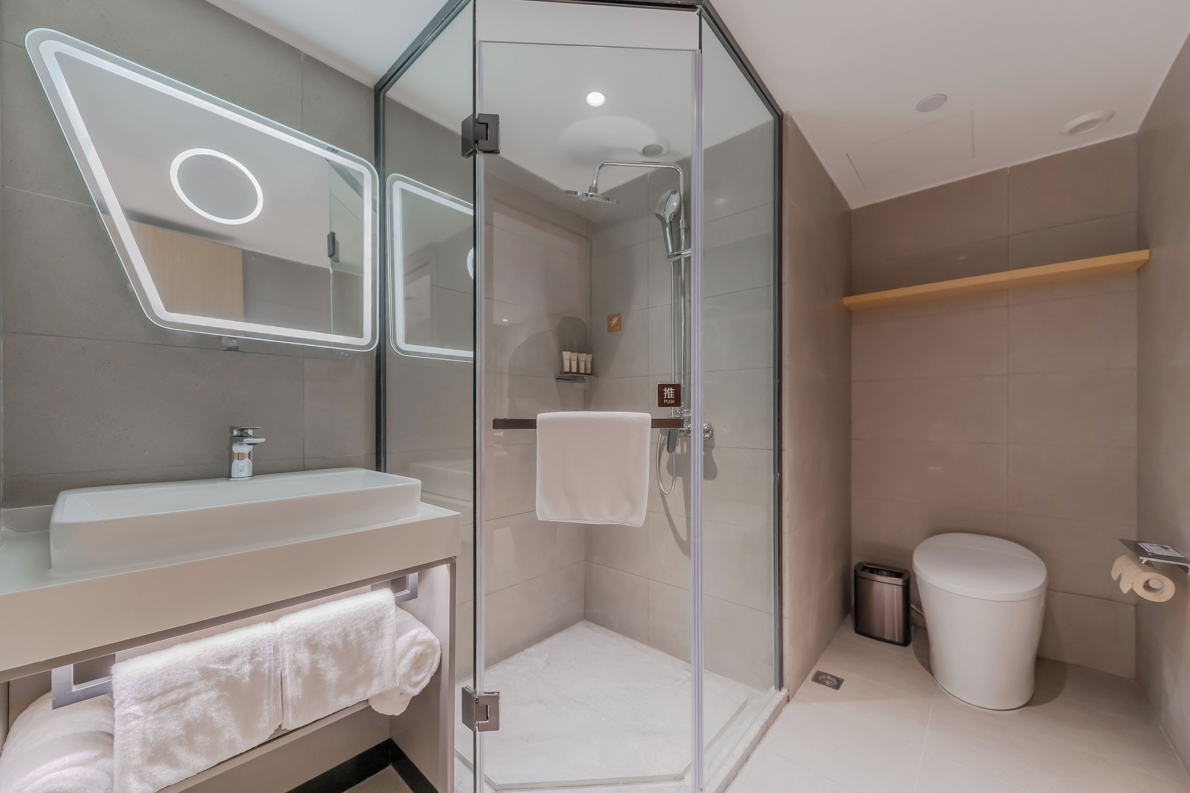 Ein modernes Badezimmer mit einer Duschkabine aus Glas, einem weißen Waschbecken und einer Toilette.