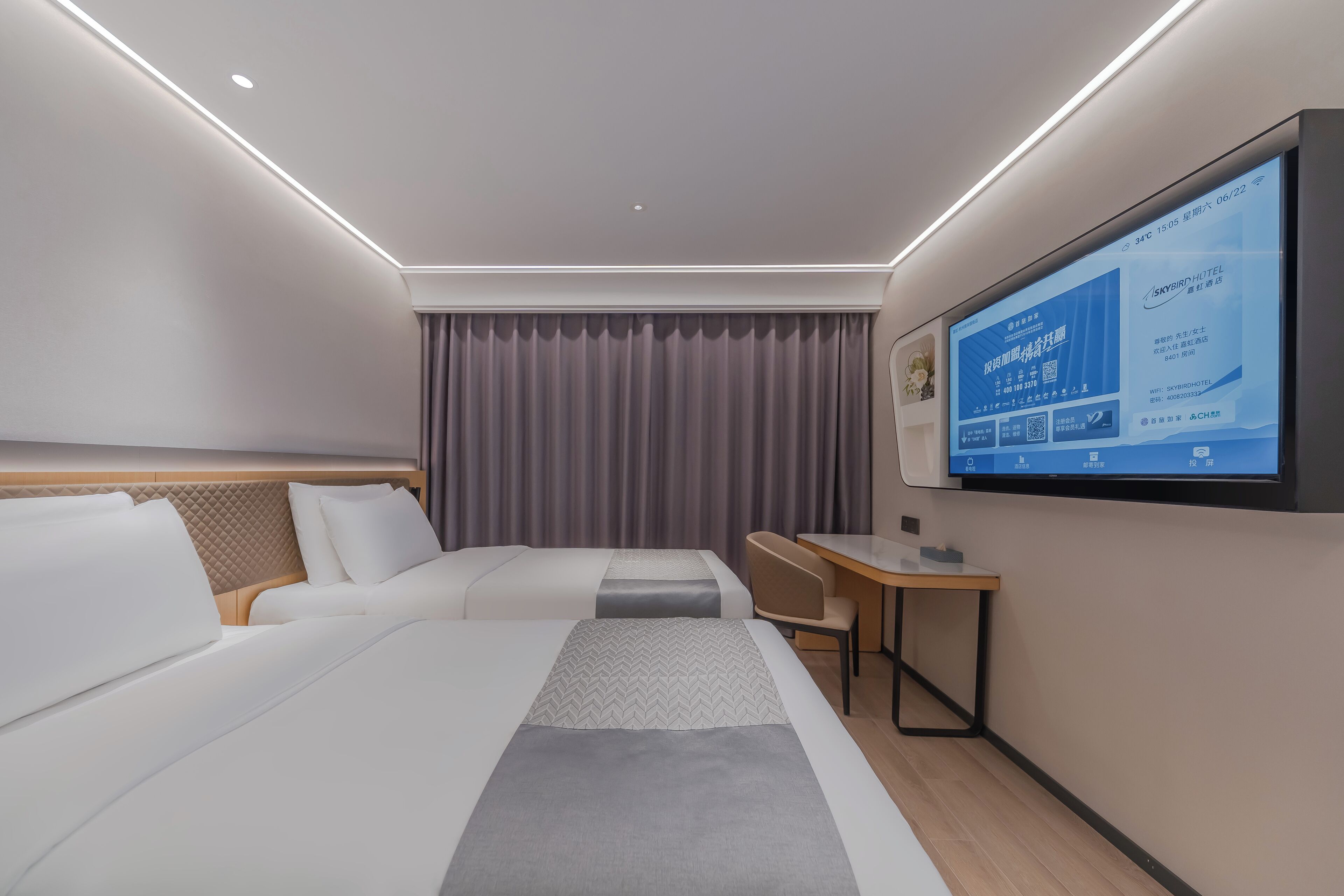 Una habitación de hotel moderna con una cama grande, un escritorio y un televisor que muestra información de la habitación.