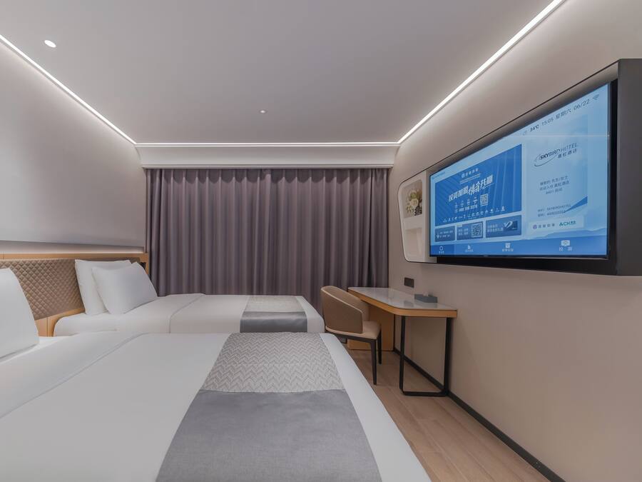 Una habitación de hotel moderna con una cama grande, un escritorio y un televisor que muestra información de la habitación.