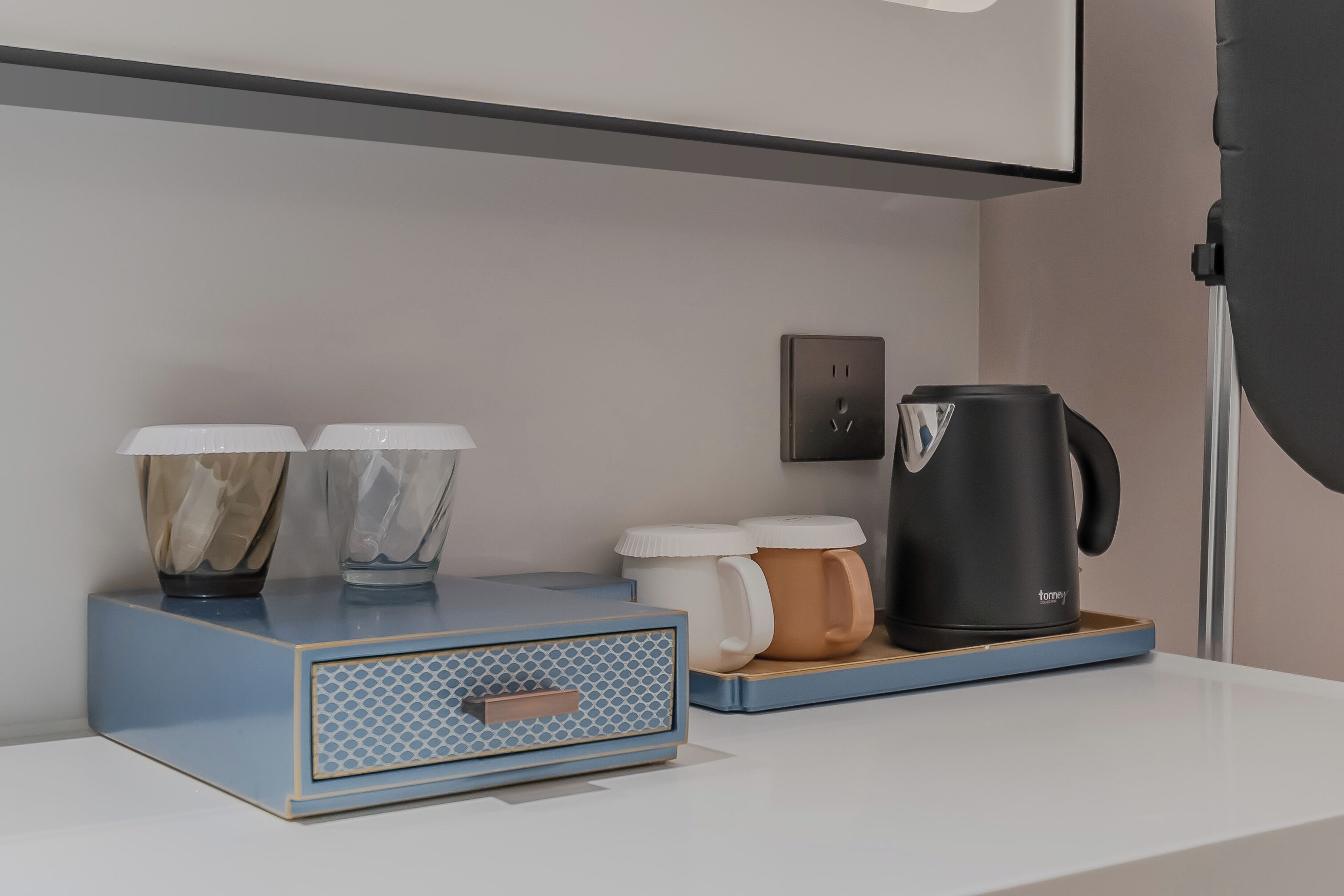 Un comptoir de cuisine moderne avec une machine à café, deux tasses et une boîte munie d’une anse.