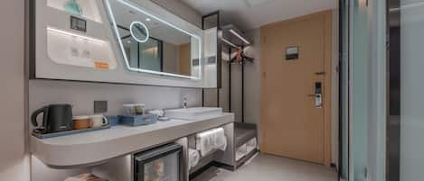 A modern bathroom with a large mirror, a sink, a coffee maker, and a towel rack.