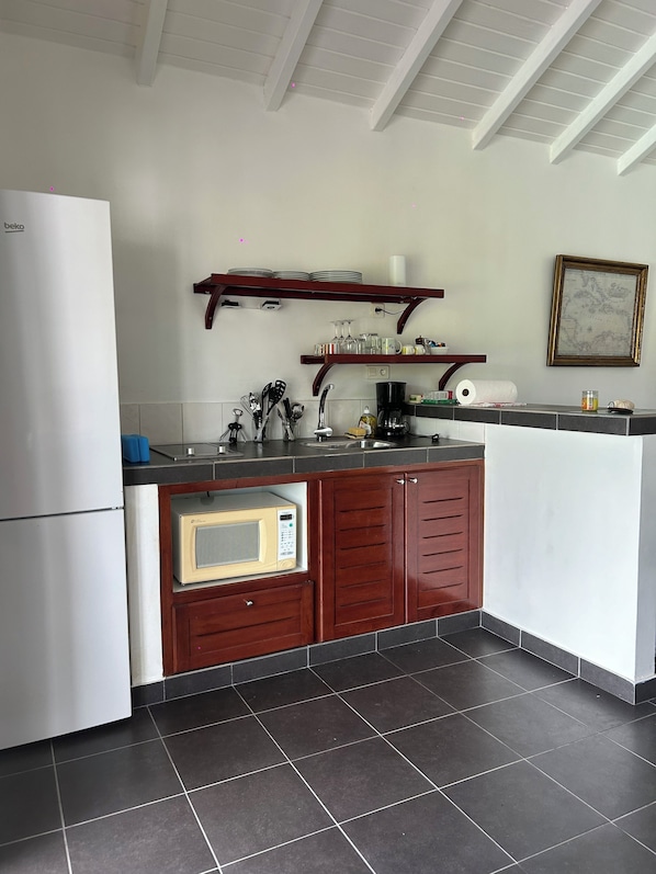 A compact kitchen with a refrigerator, microwave, sink, and wooden cabinets.