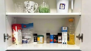 A kitchen with a coffee maker, kettle, sugar packets, and a water jug on the countertop.