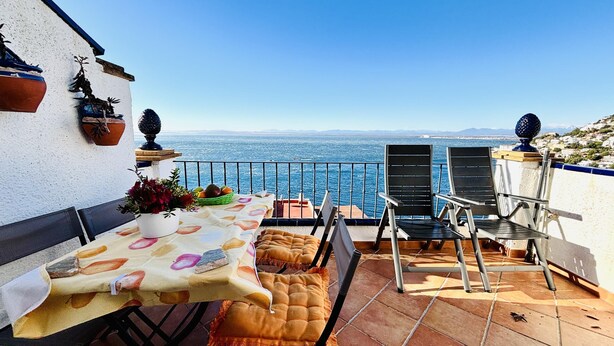Eine Terrasse mit Esstisch, Stühlen und Topfpflanzen.