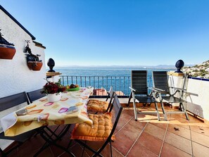 Eine Terrasse mit Esstisch, Stühlen und Topfpflanzen.