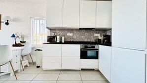 Eine moderne Küche mit weißen Schränken, einer schwarzen Arbeitsplatte und einer gemusterten Spritzschutzwand.