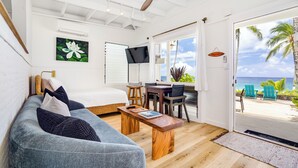 Una habitación con una cama, un sofá, una mesa de comedor y vista al océano.
