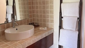 Ein Badezimmer mit einem runden Waschbecken, einem Spiegel und einem Handtuchhalter.