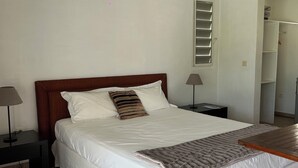 Ein Schlafzimmer mit einem großen Bett, zwei Nachttischen, einem kleinen Tischchen, Holzboden und einer geneigten Decke.