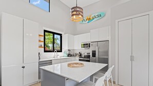 Una cocina moderna con armarios blancos, una isla central y una lámpara colgante.