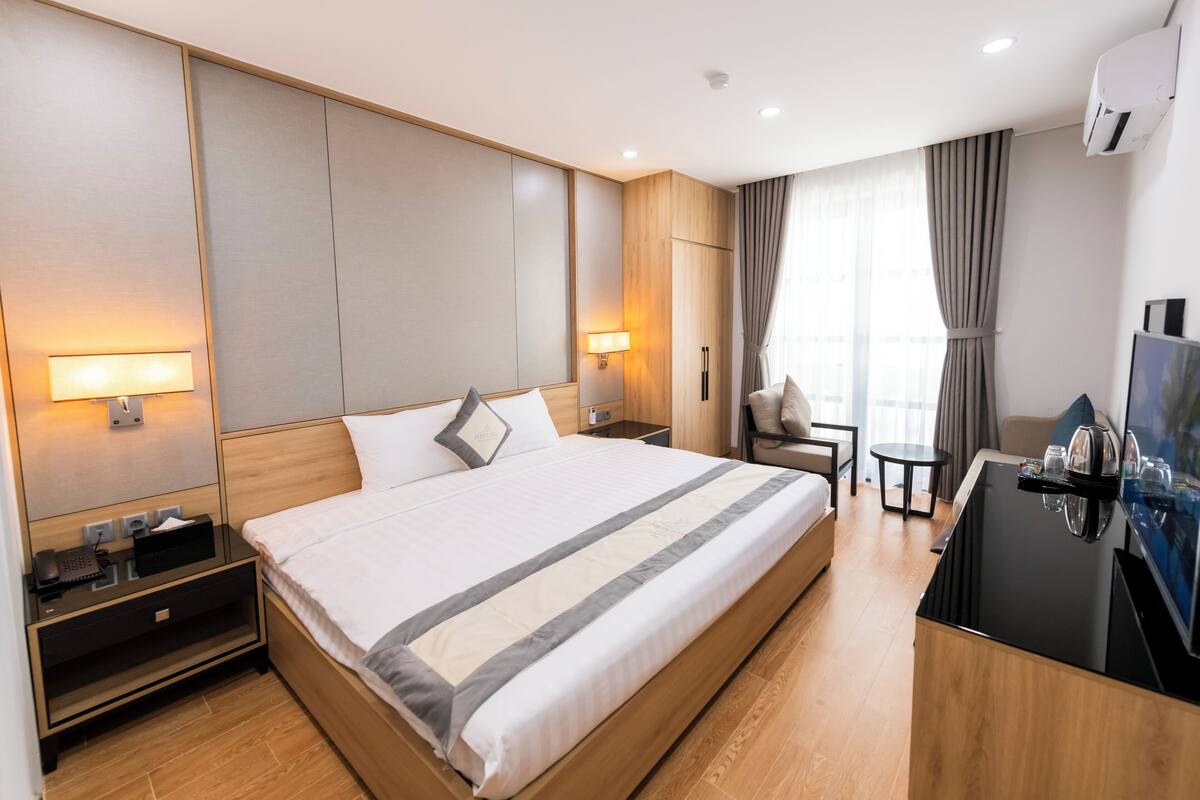 Une chambre d’hôtel moderne avec un grand lit, des tables de chevet, un bureau avec une chaise et un téléviseur.