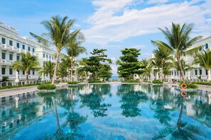 A swimming pool with palm trees and a building with balconies. - Herring Beach Hotel Phu Quoc (Duong To)