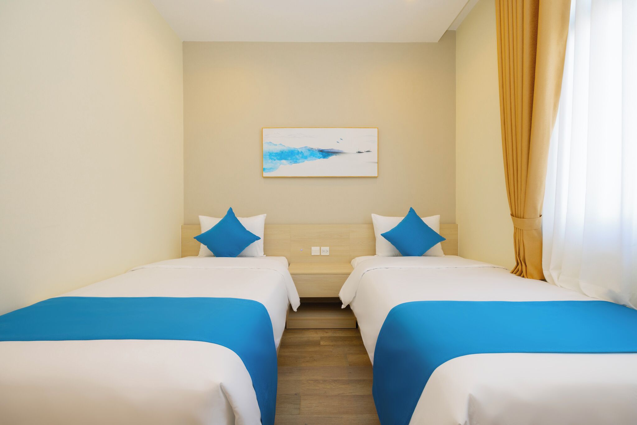 Habitación de hotel con dos camas, un cuadro en la pared y una ventana con cortinas.