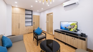 Een moderne woonkamer met een bank, een fauteuil, een salontafel, een televisie en ingebouwde houten kasten.