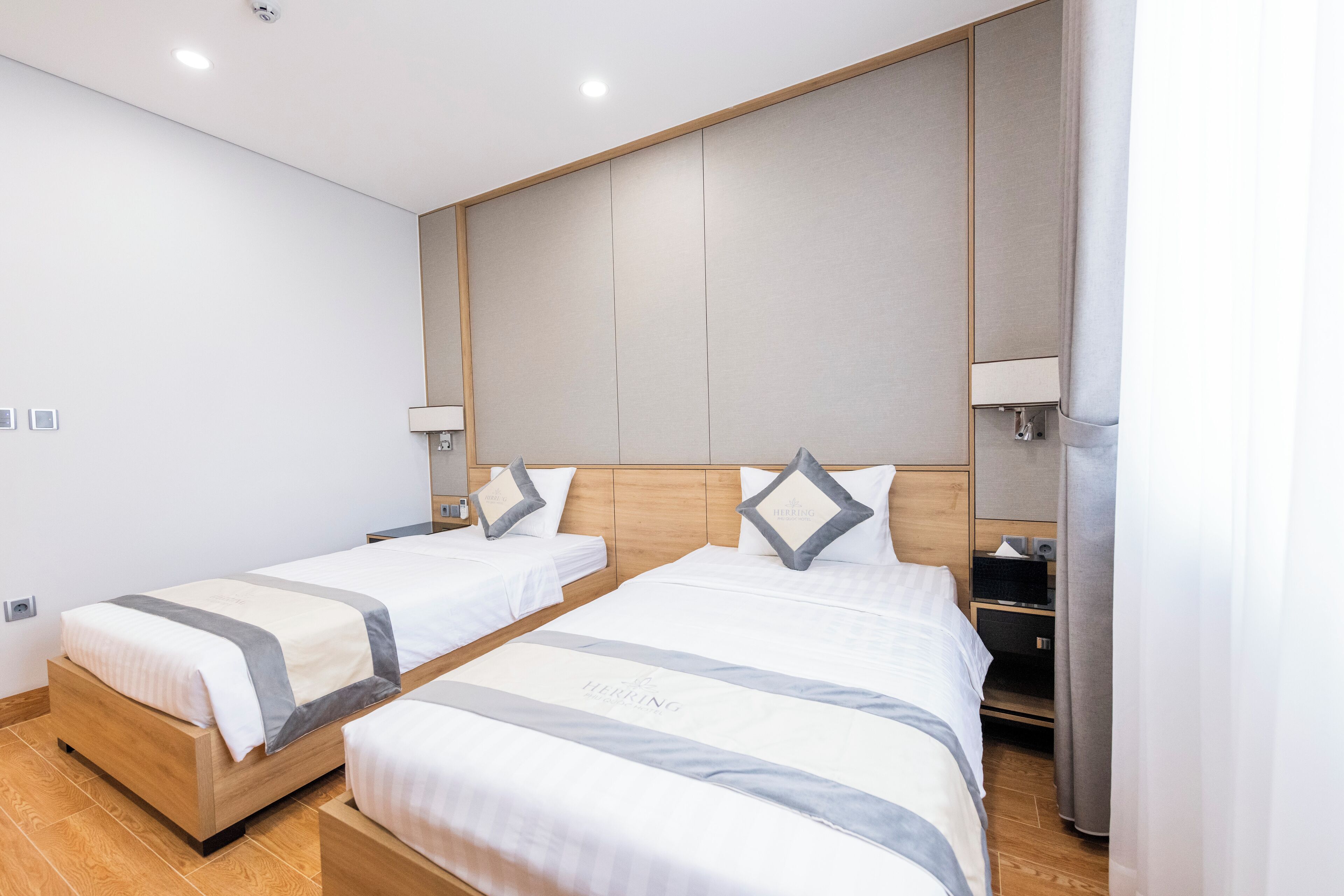 Een hotelkamer met twee bedden, houten hoofdborden en bedlampjes.