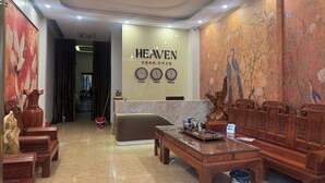 A spacious lobby with a high ceiling, a central seating area, and a wall clock displaying time in Seoul, Hanoi, and Beijing. - Heaven Hotel (Vu Ninh)