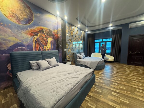 Un dormitorio con dos camas, un mural en la pared y vistas de la ciudad a través de la ventana.