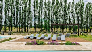 Un área de piscina con sillones reclinables y una pérgola.