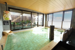 Une piscine intérieure dotée d’une terrasse en bois, de grandes fenêtres et offrant une vue sur l’extérieur.
