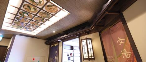 A traditional interior with a ceiling featuring a grid of decorative panels, wooden beams, and a sliding door with a red sign.